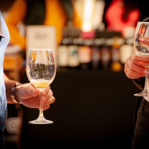 Personas sosteniendo copas de vino en un ambiente elegante y profesional, ideal para eventos empresariales, donde el networking y la experiencia gastronómica se combinan en un entorno único